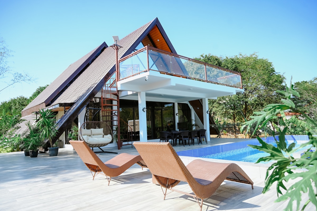 The Frame A-frame cabin exterior with pool and rattan lounge chairs