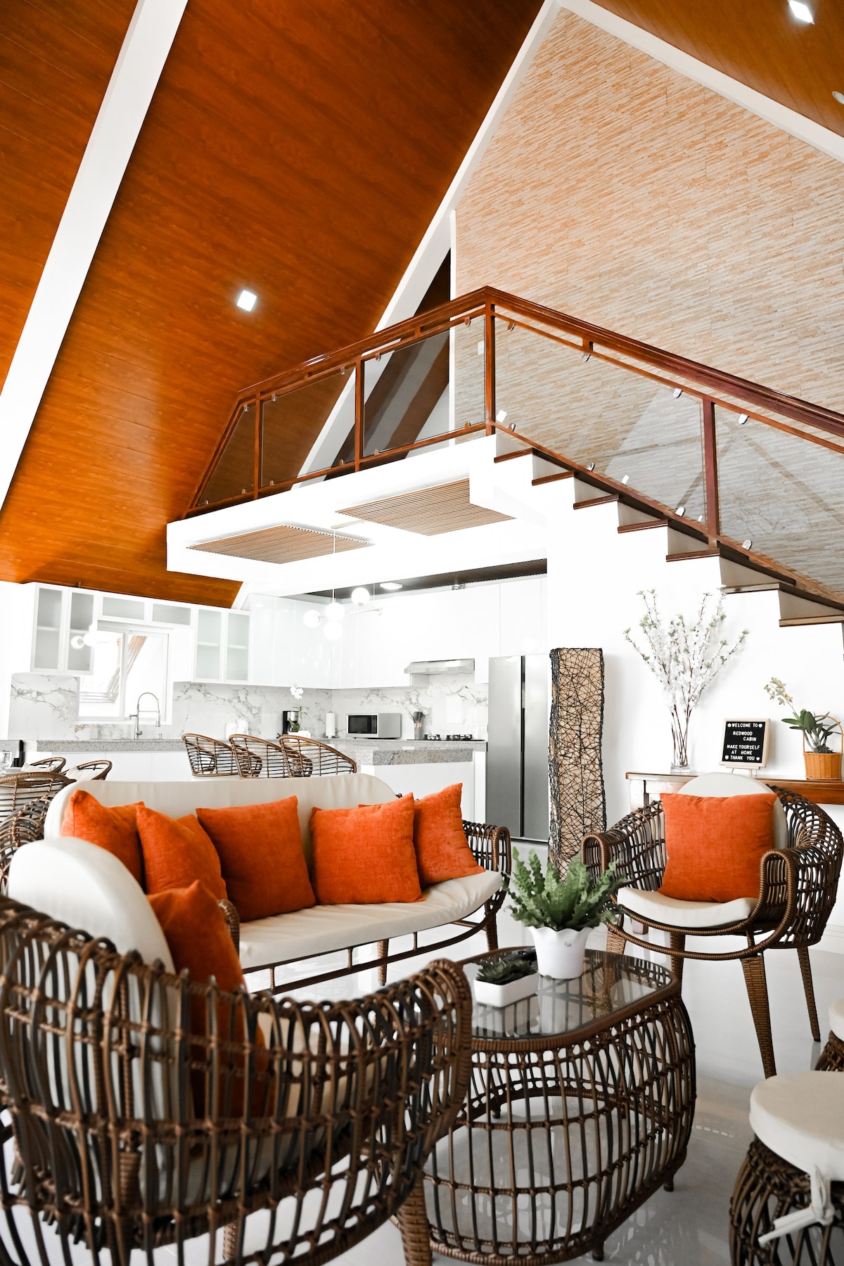 A-frame cabin interior with loft, rattan furniture, and kitchen